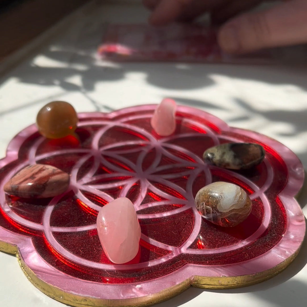 Crystal grid with stones on a red and pink mirror crystal plate