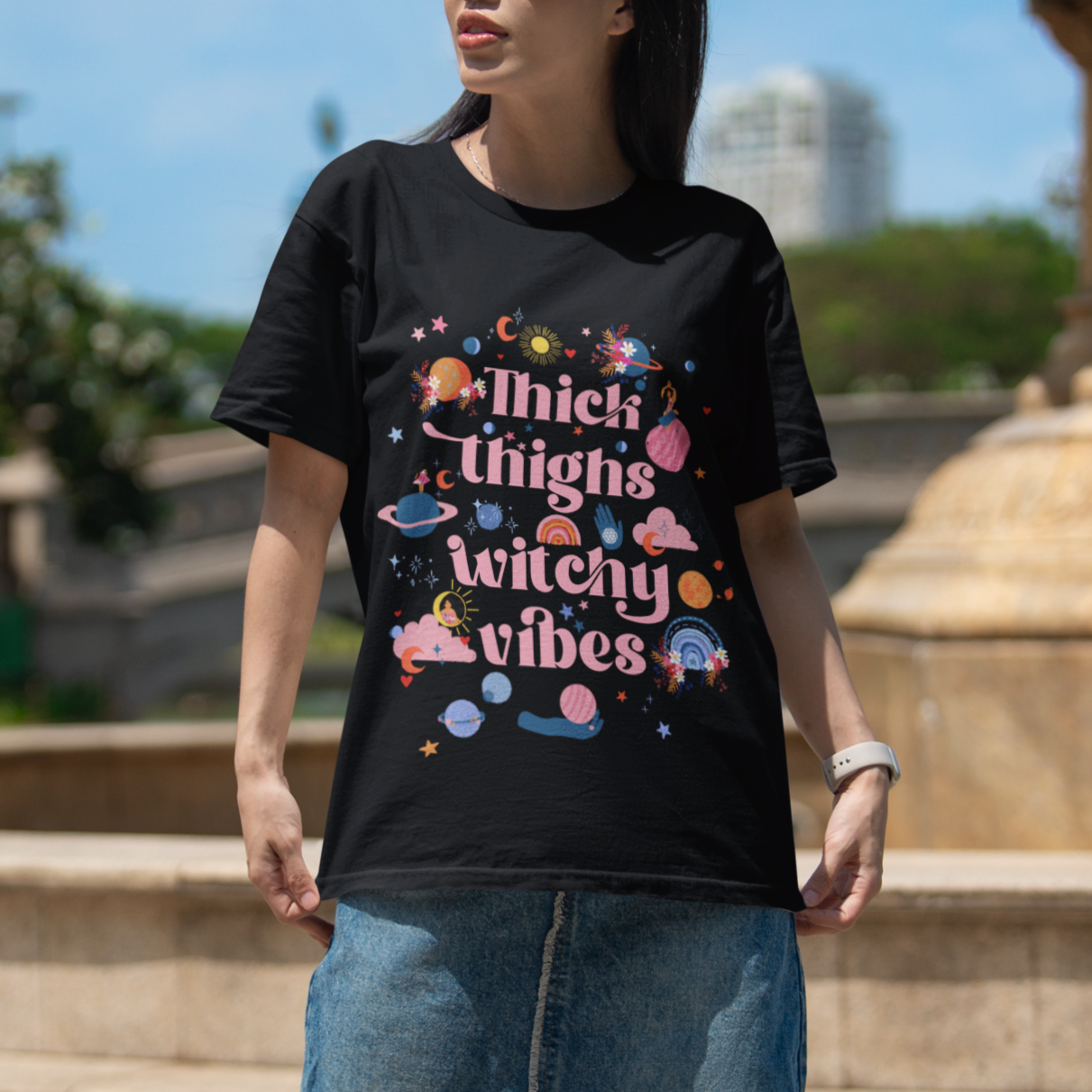 woman wearing a body positive black t-shirt with colourful text saying thigh thighs and witchy vibes