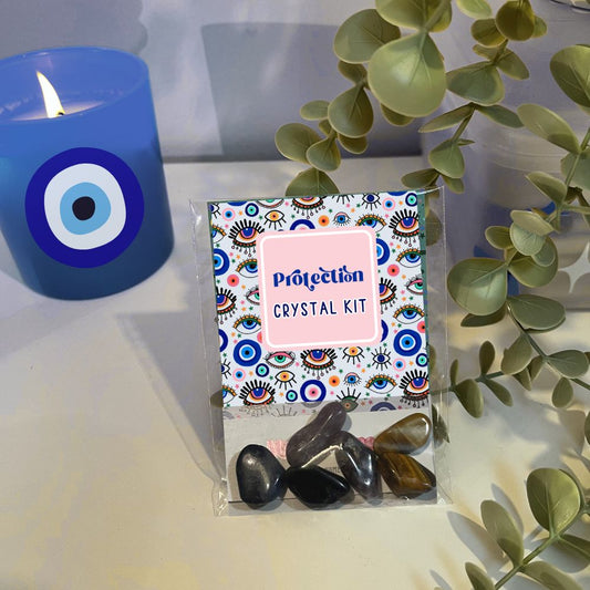 Crystal kit with colorful packaging labeled 'Protection' next to a blue candle with an evil eye design.